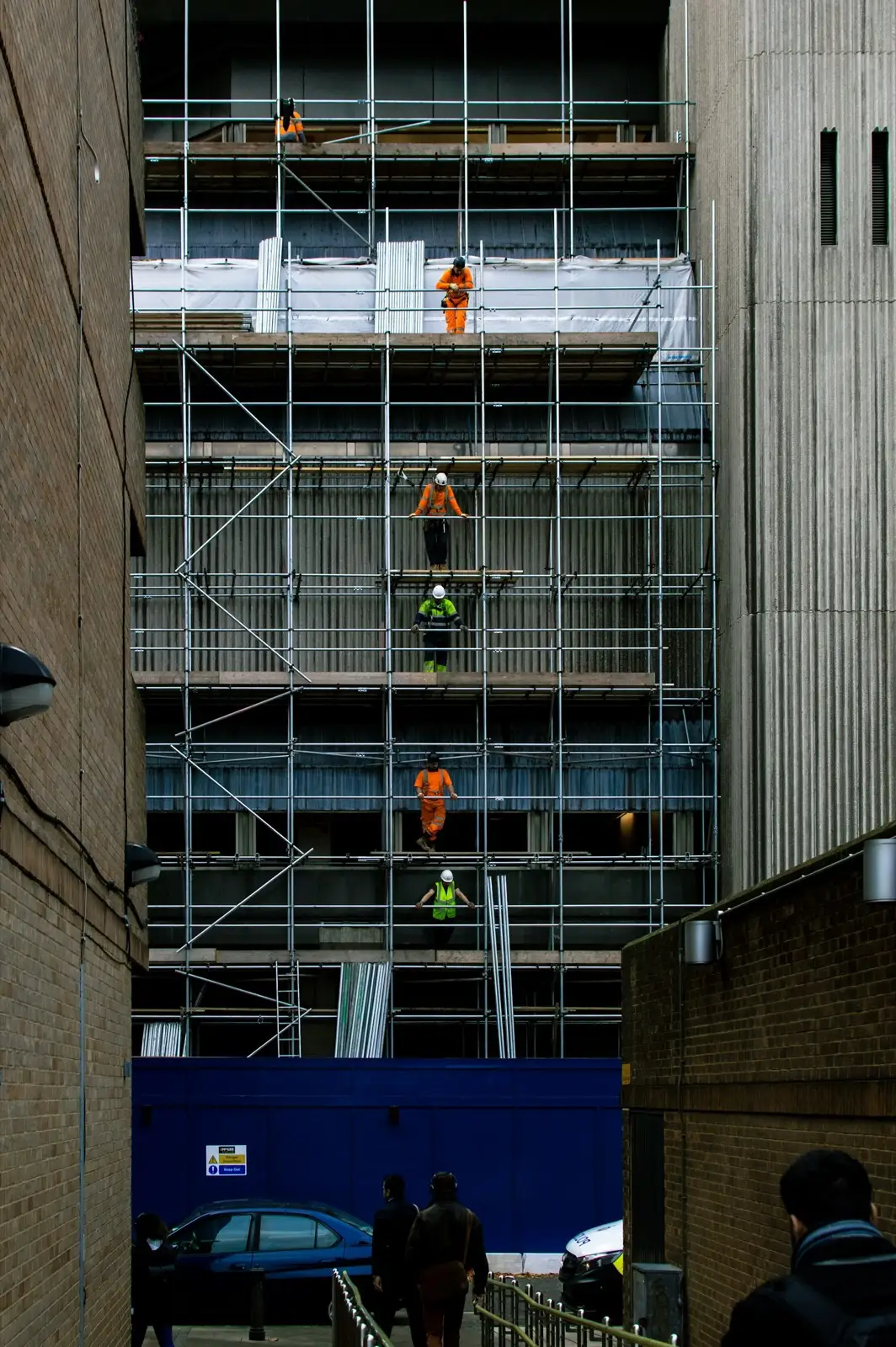 Workers on stacked scaffold levels along the face of a building