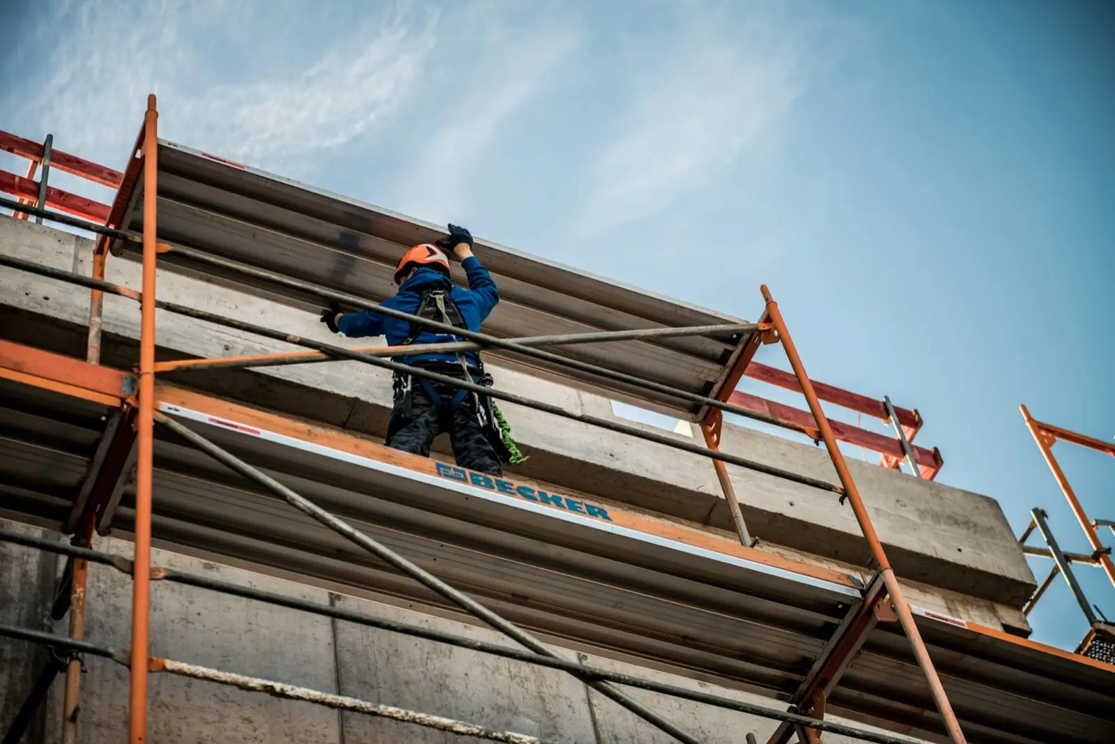 A worker on a scaffold platform fitted along a building under construction