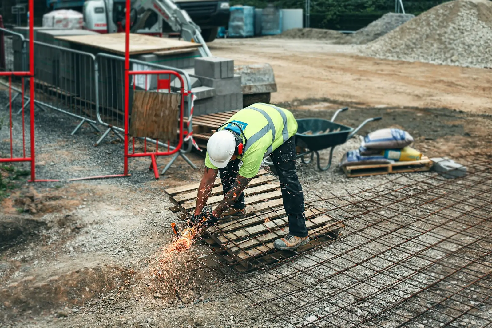 A worker in a high-visibility vest cutting steel on a construction site