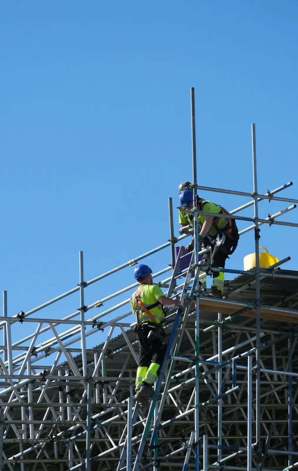 Workers in high-visibility gear building a scaffold lift